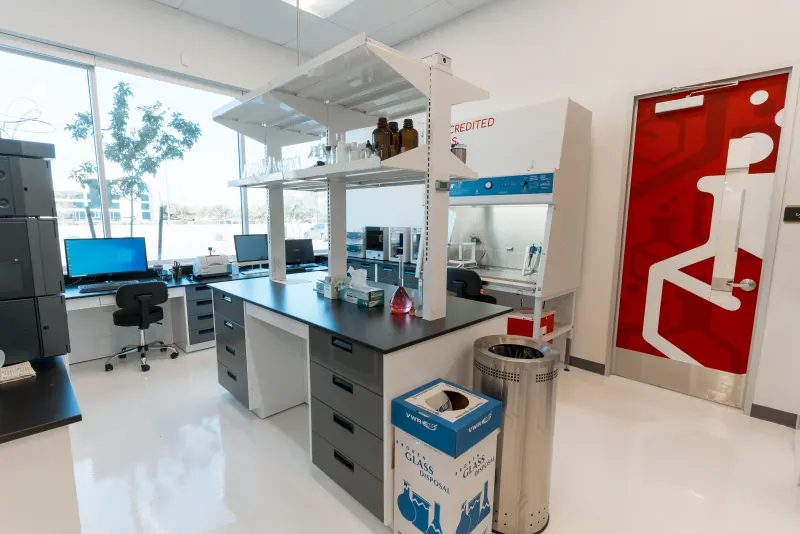 Inside the Adept Life Sciences ISO-accredited analytical lab — benchtop with HPLC and fume hood